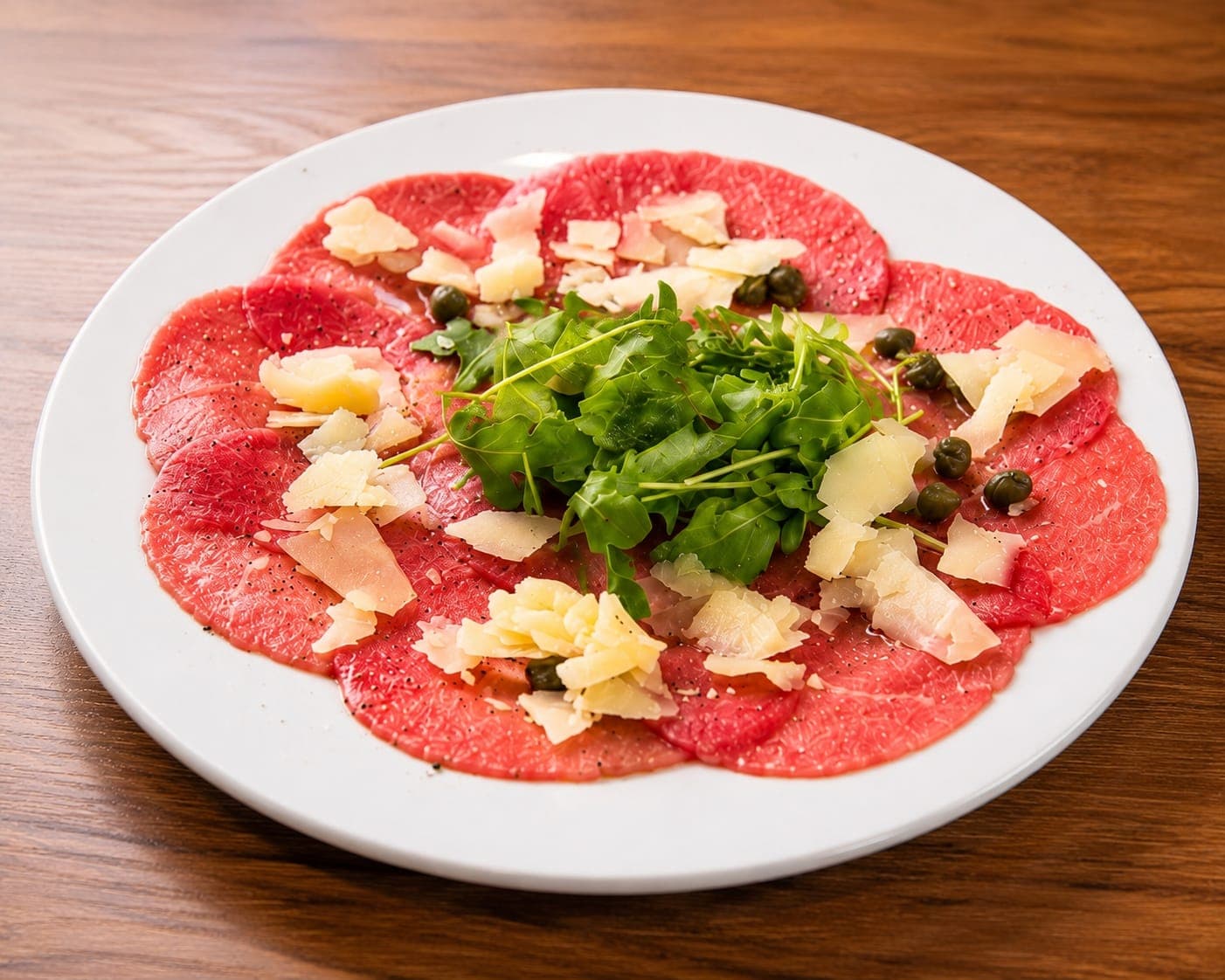 Carpaccio de buey con rúcula, parmesano, aceite de oliva y alcaparras